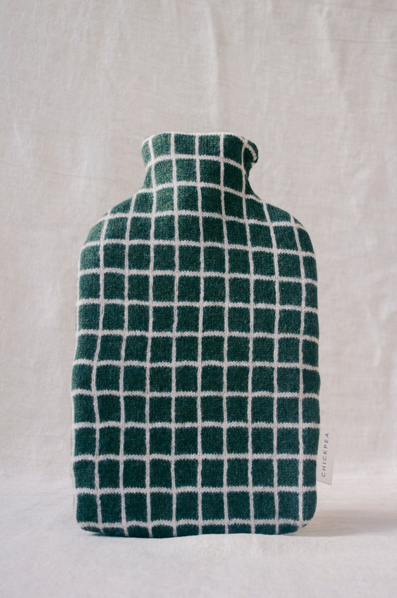 Green checkered hot water bottle on a light gray background