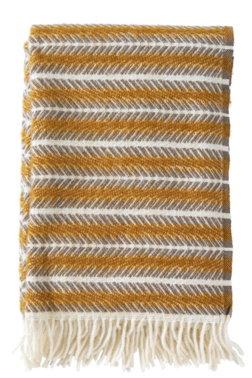 Soft lambswool blanket with an abstract stripe design. Amber, cream and grey colours. Finished with a tassel trim