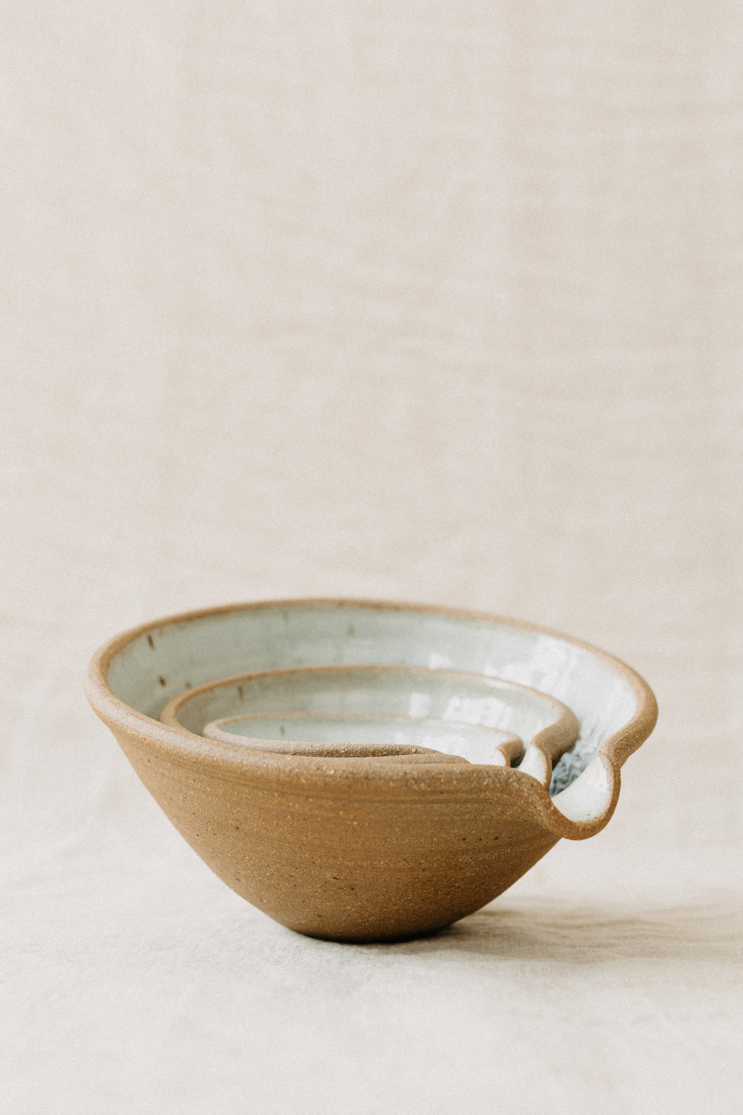 Handmade by the Leach Pottery Studio in St Ives. A set of three mixing bowls each finished with a lip for pouring. These bowls are glazed on the inside with a very pale duck egg blue dolomite glaze. The outside is unglazed for a natural and organic feel. Neatly stacked inside each other in this photo