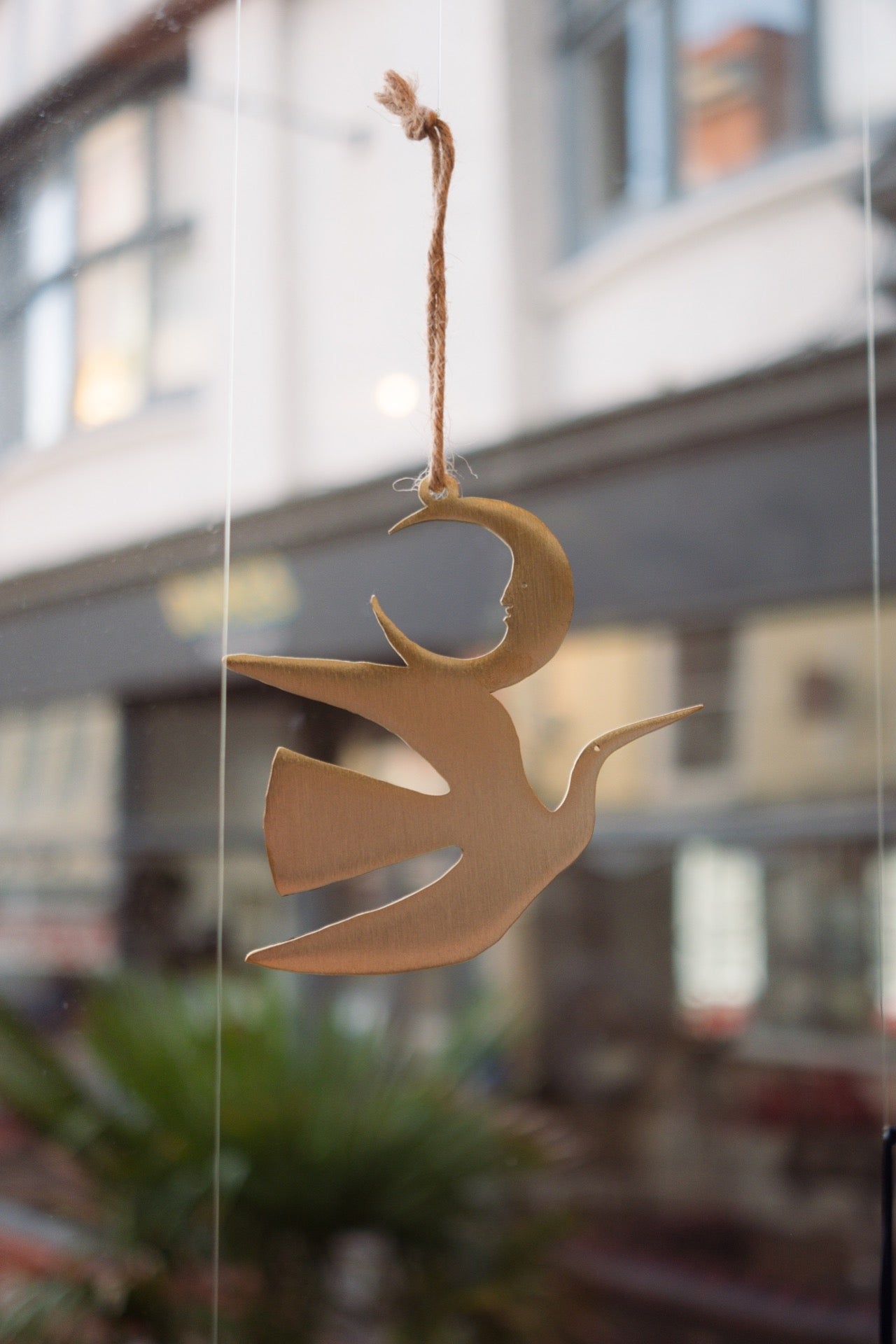 Decorative angel hanging ornament on a blurred city street background