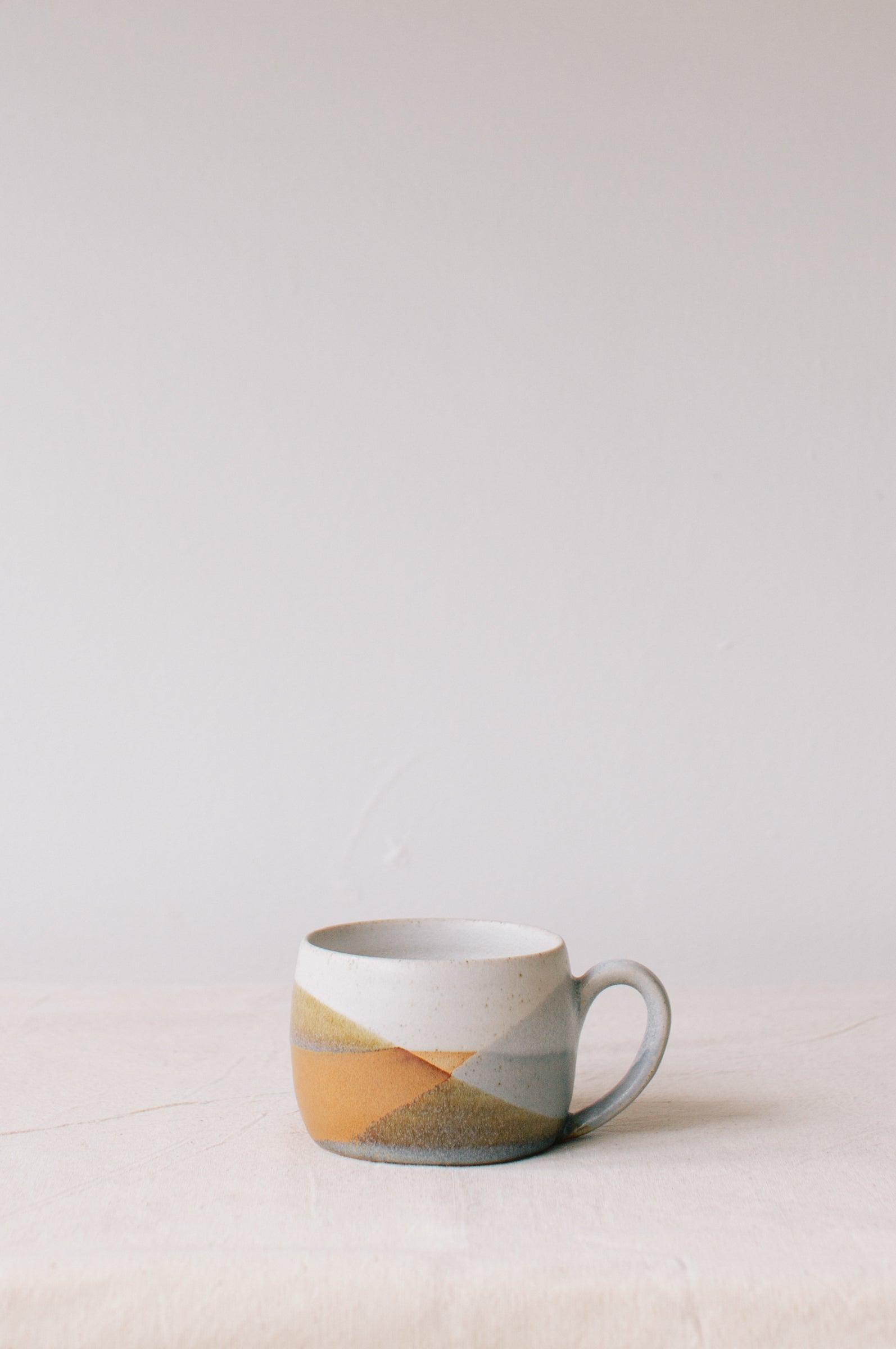 Handmade ceramic mug by Liz Vidal. Liz uses different tones of rust and brown glaze to dip her mug to create an abstract landscape design.