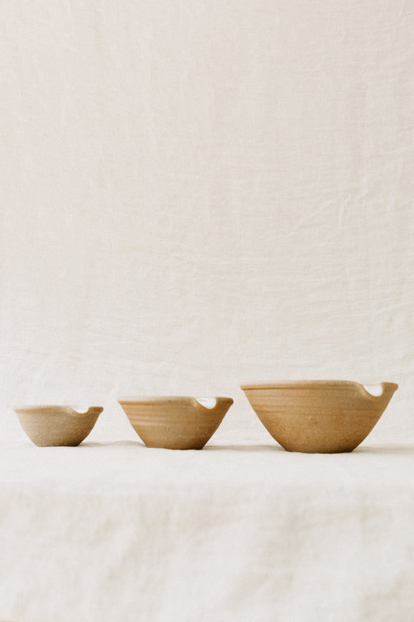 Handmade by the Leach Pottery Studio in St Ives. A set of three mixing bowls each finished with a lip for pouring. These bowls are glazed on the inside with a very pale duck egg blue dolomite glaze. The outside is unglazed for a natural and organic feel. Displayed in a line from small on the left to large on the right