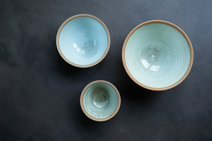 Handmade by the Leach Pottery Studio in St Ives. A set of three prepping bowls each one is glazed on the inside with a duck egg blue dolomite glaze. The outside is unglazed for a natural and organic feel. Displayed side by side in this image sitting to show the inside colour of the glaze.