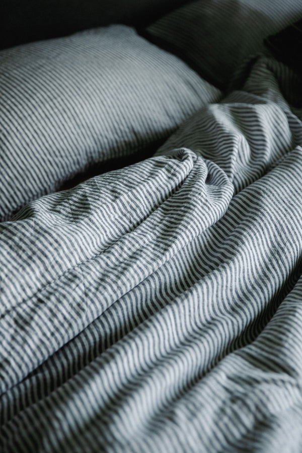 Close up image of linen stripe white and grey bedding from Ondine Ash, Falmouth
