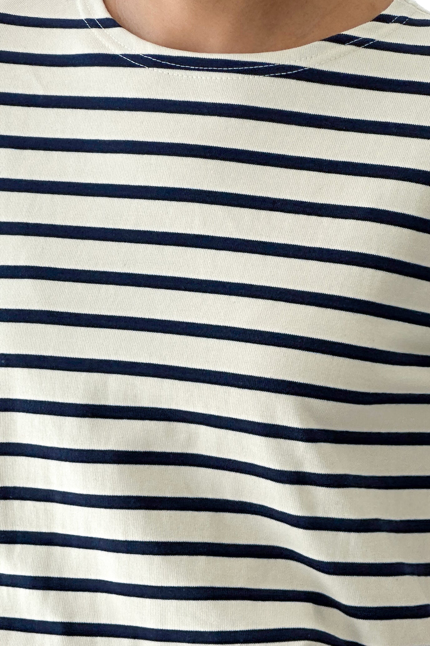 Close-up of a person wearing a white and navy striped shirt.