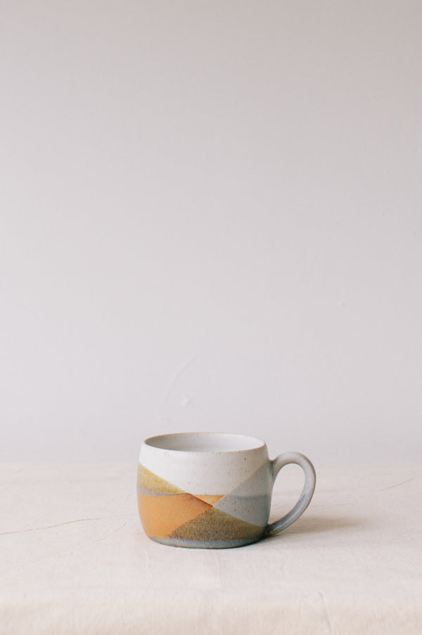 Handmade ceramic mug by Liz Vidal. Liz uses different tones of rust and brown glaze to dip her mug to create an abstract landscape design.