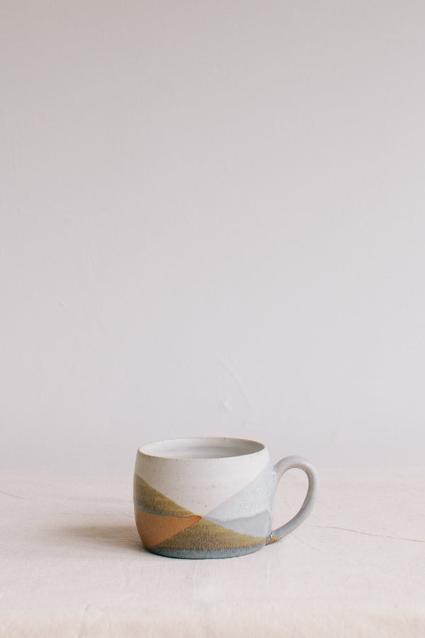 Handmade ceramic mug by Liz Vidal. Liz uses different tones of rust and brown glaze to dip her mug to create an abstract landscape design.