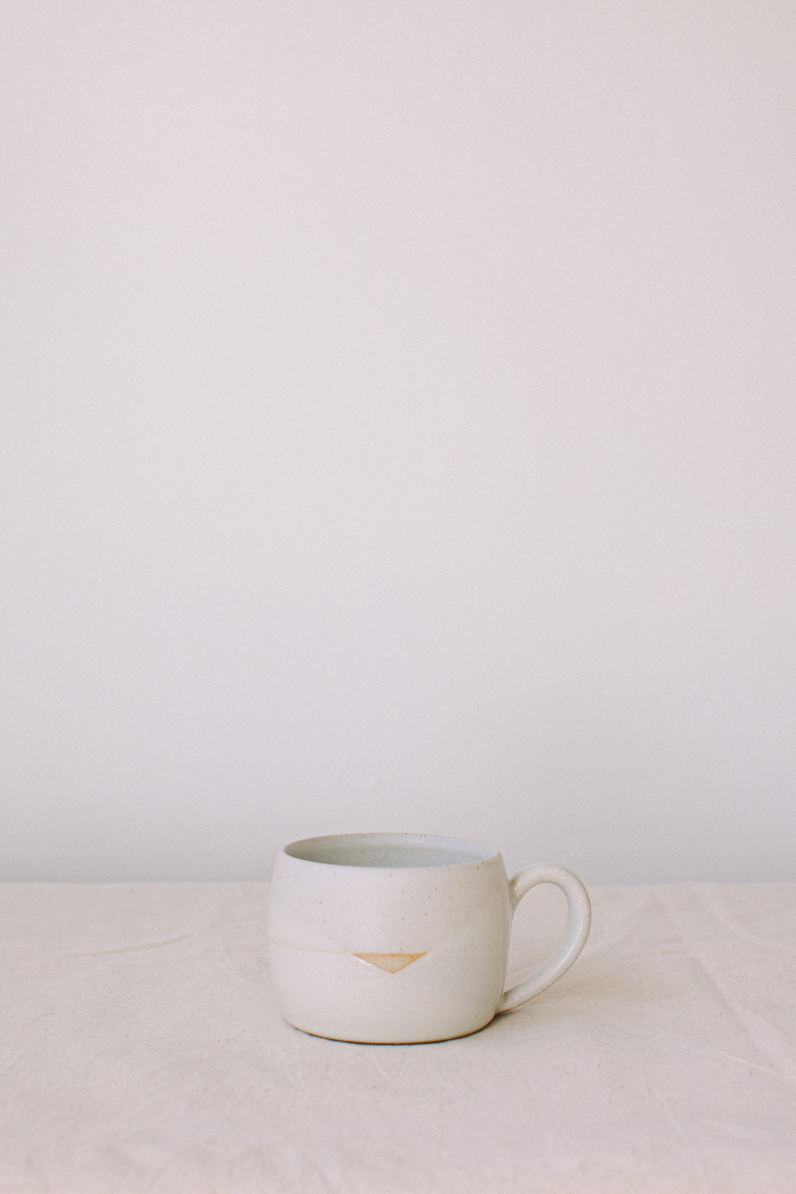 Handmade ceramic mug by Liz Vidal. Liz uses different tones of white glaze to dip her mugs to create an abstract landscape design.