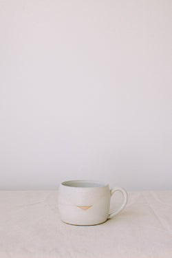 Handmade ceramic mug by Liz Vidal. Liz uses different tones of white glaze to dip her mugs to create an abstract landscape design.