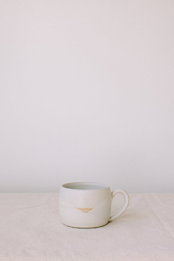 Handmade ceramic mug by Liz Vidal. Liz uses different tones of white glaze to dip her mugs to create an abstract landscape design.
