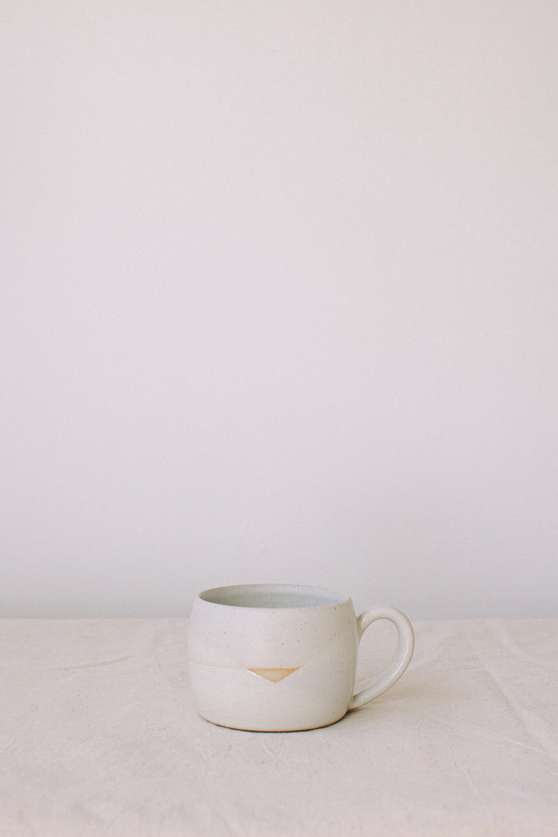Handmade ceramic mug by Liz Vidal. Liz uses different tones of white glaze to dip her mugs to create an abstract landscape design.
