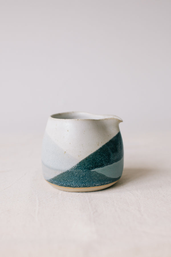 Handmade ceramic jug by Liz Vidal. Liz uses different tones of blue glaze to dip her jugs to create an abstract landscape design.