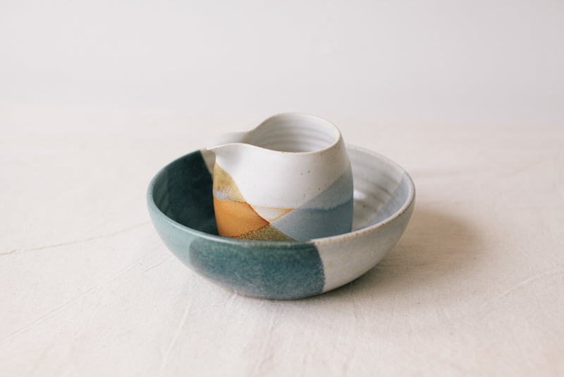 Handmade ceramic bowl by Liz Vidal. This bowl is the perfect size for breakfast, salads or soups. Liz uses different tones of blue glaze to dip her bowls to create an abstract landscape design. Photographed here with the rust jug