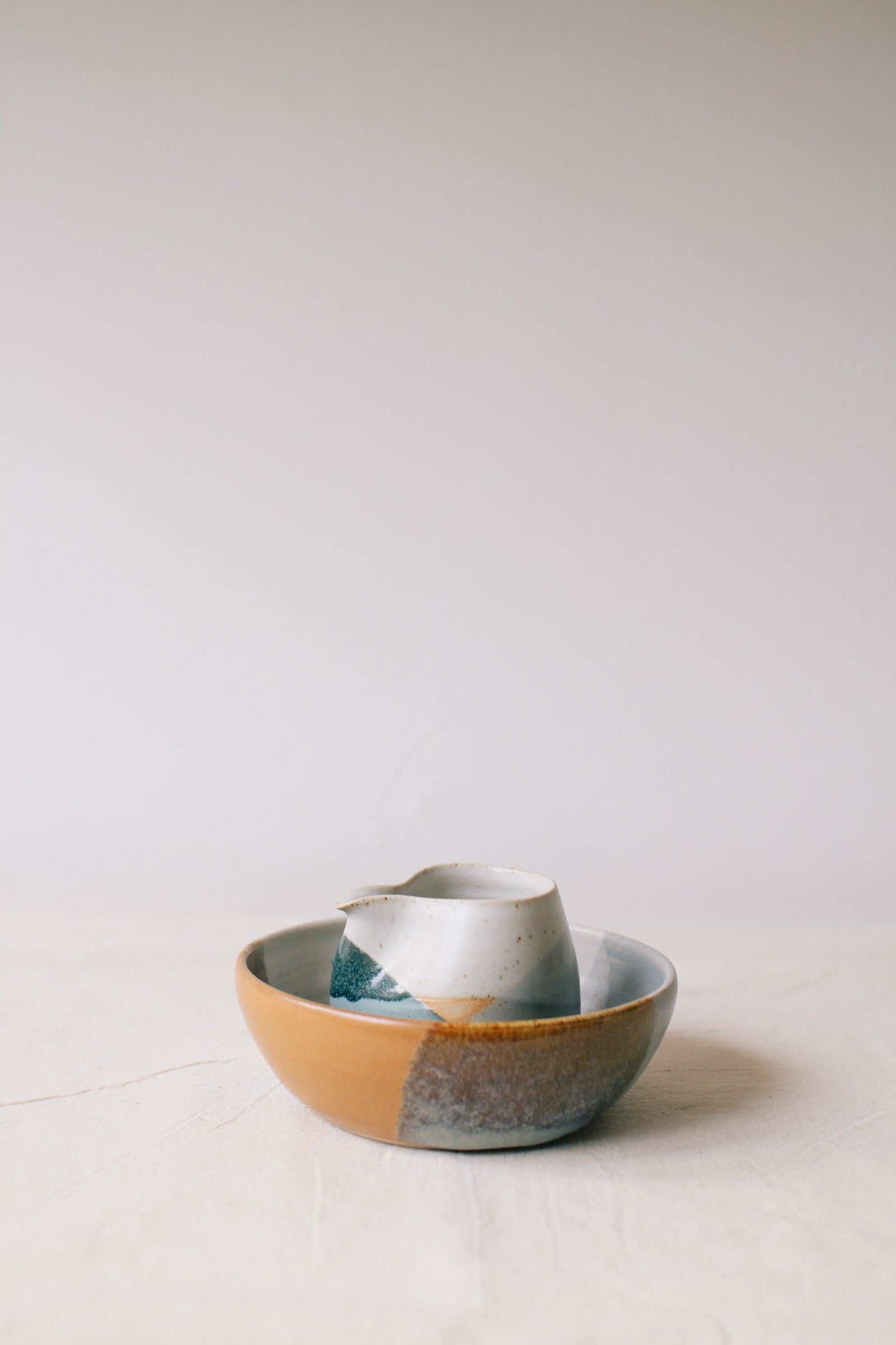 Handmade ceramic bowl by Liz Vidal. This bowl is the perfect size for breakfast, salads or soups. Liz uses different tones of rust and brown glaze to dip her bowls to create an abstract landscape design. Photographed here with the blue jug.