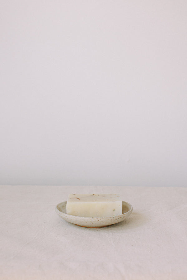 Handmade ceramic soap dish by Liz Vidal. This incense holder is a simple round shape and is finished with 3 holes and a small foot plate to allow the soap to drain. Liz has used a plain white glaze which shows small specs from the clay though it, giving it a beautiful natural finish.