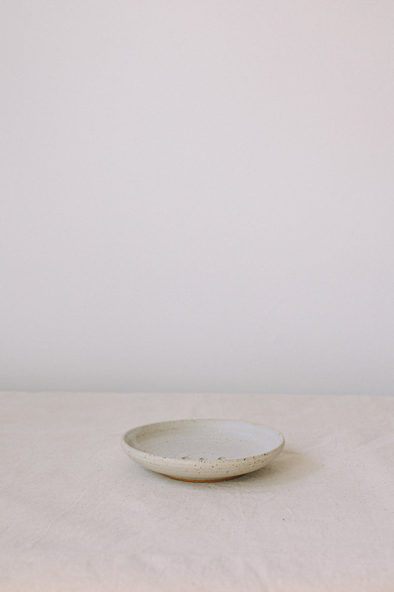 Handmade ceramic soap dish by Liz Vidal. This incense holder is a simple round shape and is finished with 3 holes and a small foot plate to allow the soap to drain. Liz has used a plain white glaze which shows small specs from the clay though it, giving it a beautiful natural finish.
